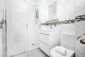 a white bathroom with a shower and a toilet at Spacious, Chic Townhouse with Parking & Garden in Birmingham +20 photos