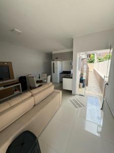 un salon avec un canapé et une cuisine dans l'établissement Casa em Itanhaém com Piscina e Ar condicionado à 900 Metros da Praia, à Itanhaém