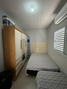 - une petite chambre avec 2 lits et une armoire dans l'établissement Casa em Itanhaém com Piscina e Ar condicionado à 900 Metros da Praia, à Itanhaém