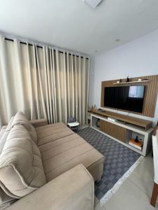 un salon avec un canapé et une télévision à écran plat dans l'établissement Casa em Itanhaém com Piscina e Ar condicionado à 900 Metros da Praia, à Itanhaém