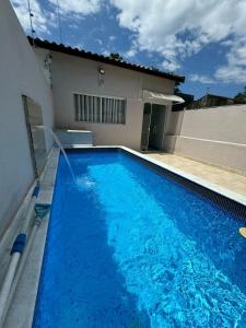 une grande piscine bleue devant une maison dans l'établissement Casa em Itanhaém com Piscina e Ar condicionado à 900 Metros da Praia, à Itanhaém 6 autres photos