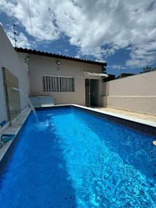 une grande piscine bleue à côté d'un immeuble dans l'établissement Casa em Itanhaém com Piscina e Ar condicionado à 900 Metros da Praia, à Itanhaém
