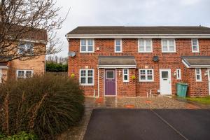 a red brick house with a purple door at Babbage House By Horizon Stays in Stockton-on-Tees