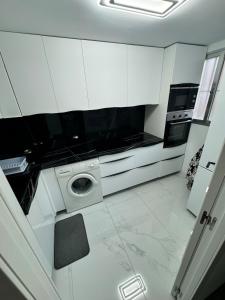 a kitchen with white cabinets and a washing machine at EliMar-Torrevieja Beach in Torrevieja +12 photos