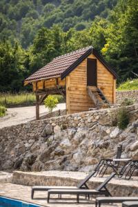 a wooden cabin with a stone wall next to a pool at Zora - moje mjesto in Konjic