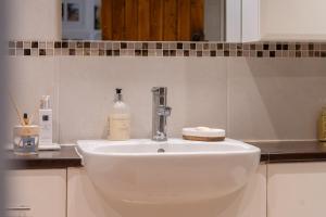 a white sink in a bathroom with a mirror at Beautiful 4-Bedroom Cottage Pass the Keys in Rickmansworth +17 photos