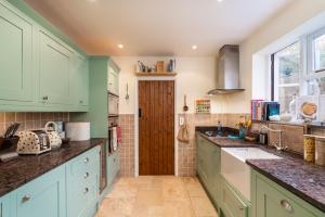 a kitchen with green cabinets and a wooden door at Beautiful 4-Bedroom Cottage Pass the Keys in Rickmansworth