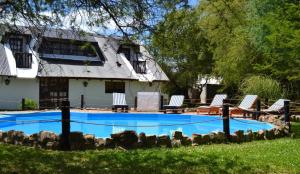 a swimming pool with chairs and a house at Valdemoro Hosteria in Gualeguaychú