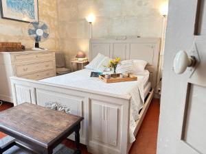 a bedroom with a white bed with a tray of flowers on it at La Maison des Hautures - Ancien Couvent avec Extérieur Proche Arénes- Idéal Familles ou groupe in Arles