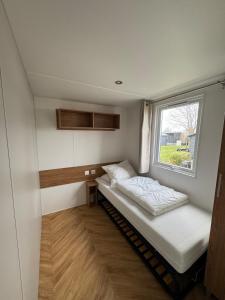 a small bedroom with a bed and a window at Gemütliches Chalet in Strandnähe in Oostkapelle