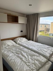 an unmade bed in a bedroom with a window at Gemütliches Chalet in Strandnähe in Oostkapelle +12 photos