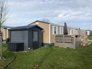 a house with a deck and a black shed at Gemütliches Chalet in Strandnähe in Oostkapelle