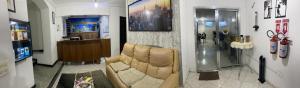 a living room with a leather couch and a television at Hostel Anprado 4 kit café incluso, Próx-Aeroporto de Guarulhos in Guarulhos
