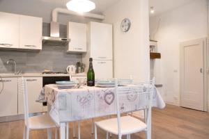 Una cocina con una mesa con sillas y una botella de vino. en Maison Simona Lago Maggiore, en Orino