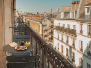 a table with a plate of food and drinks on a balcony at Hôtel du Savoir in Paris