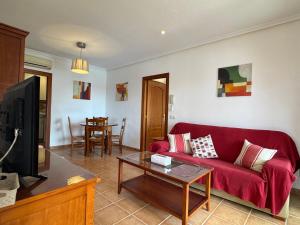 a living room with a red couch and a table at Apartamento Al Andalus Hill - Vera Playa in Vera