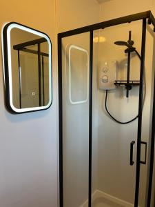 eine weiße Tür mit Spiegel und Dusche in der Unterkunft Pabay View in Breakish + 21 Fotos
