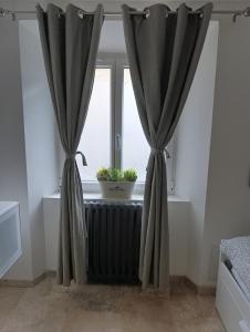 a window with a black curtain and a plant on a radiator at Logement le gabian in Ampus +1 photo