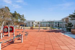 an empty playground with swings and a building in the background at GRANO FLATS - Sobieszewo - Pino Resort in Gdańsk +101 photos