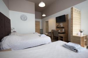 a hotel room with two beds and a desk and a television at Rooms Rebolj in Osijek