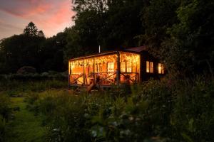 a house lit up with lights in a field at Luxury Off-Grid Cabin with Outdoor Bath in Scotland in Clachan of Campsie