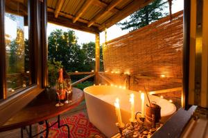 a bathroom with a tub and candles on a balcony at Luxury Off-Grid Cabin with Outdoor Bath in Scotland in Clachan of Campsie