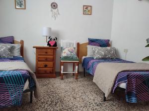 a bedroom with two beds and a dresser and a chair at un nid au soleil in Puerto de Santiago