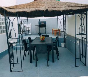 a table and chairs in a room with a thatched roof at un nid au soleil in Puerto de Santiago