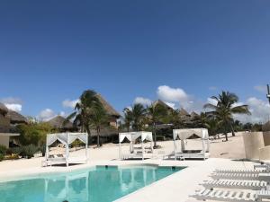 una piscina con sillas blancas y una playa en Beach House Fortamu, en Watamu