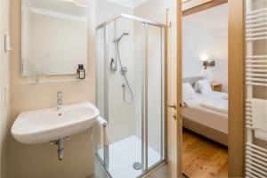 un bagno con lavandino e doccia e un letto di Hotel Greif a Malles Venosta