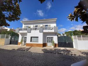 a white house with a balcony on a street at Maison de vacances Casa Rocha in Armação de Pêra