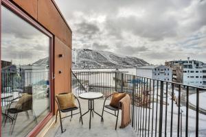 a balcony with a table and chairs and mountains at TotalApartments Vervet Apartment Hotel in Tromsø