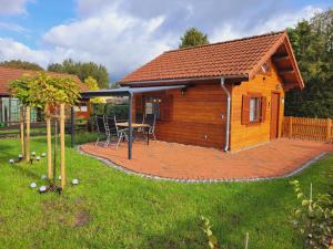 a wooden cabin with a table and chairs in a yard at Christinas kleines, gemütliches Ferienhaus in Neudorf Rodewald
