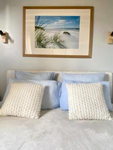 a bed with two pillows and a picture of a beach at Le Clos de la Barre- Chambres d'hôtes de charme en Normandie-BASLY-Proche plage débarquement in Basly