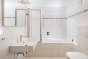 a white bathroom with a sink and a bath tub at Appartements Greif in Malles Venosta +8 photos