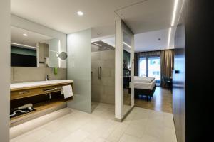 un bagno con lavandino e doccia e una camera da letto di Montfort - das Hotel a Feldkirch