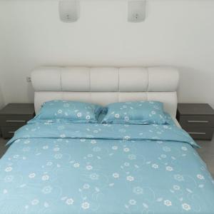 a bed with a blue comforter and two night stands at Vera's Apartment in Timişoara