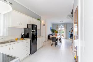 eine Küche mit weißen Schränken und einem schwarzen Kühlschrank in der Unterkunft Beachfront Bliss by halu! Spacious vacation house in Nea Skioni