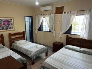 een slaapkamer met twee bedden en twee ramen bij Pousada & Camping Santa Clara in Santa Helena