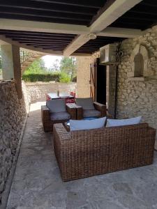 a patio with wicker chairs and tables on a stone wall at Domaine de la Tour de Pérès in Ayguetinte