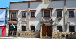 un gran edificio blanco con puertas y ventanas marrones en Hotel La Giralda en Salta