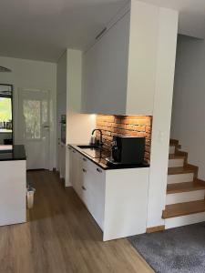 a kitchen with white cabinets and a brick wall at Ceglany Domek z jacuzzi, nad jeziorem, przy lesie in Tomaszkowo