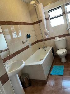 a bathroom with a toilet and a tub and a sink at Amber suites in Nairobi +20 photos