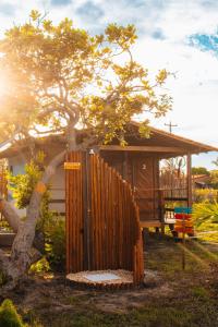 a wooden fence in front of a house with a tree at Pousada Rancho Matos in Santo Amaro