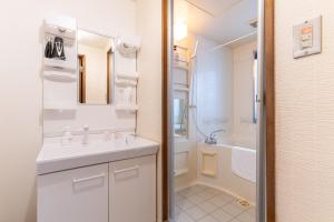 Un baño blanco con lavabo y ducha. en 天満橋 Guest House#有电梯 #步行大阪城 #赏樱花必打卡点 #直达梅田 京都 #免费wifi, en Osaka 128 fotos más