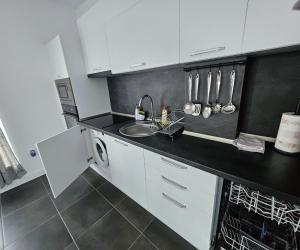 a kitchen with white cabinets and a sink at Rose Garden Deluxe in Chernomorets