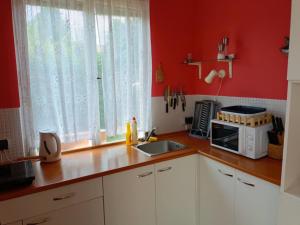 a kitchen with red walls and white cabinets and a microwave at Vířivka u Křemílka in Němčovice