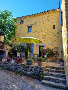 a yellow building with a patio with an umbrella at chambre dans ferme provençale in Ongles