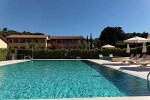 a swimming pool with chairs and umbrellas next to a house at Le Corti Del Sole Residence in Venturina Terme