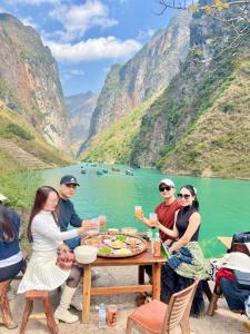un grupo de personas sentadas alrededor de una mesa de picnic junto a un lago en Rosie Homestay Hà Giang, en Ha Giang